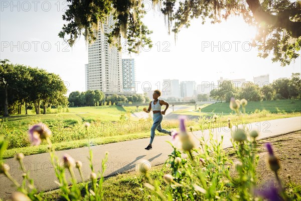 Mixed Race woman running on path in park beyond wildflowers