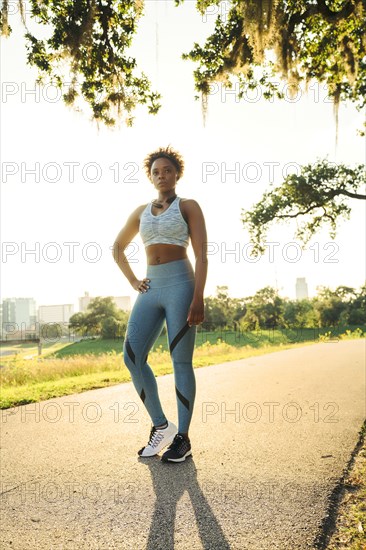 Portrait of serious mixed race woman standing on running path in park