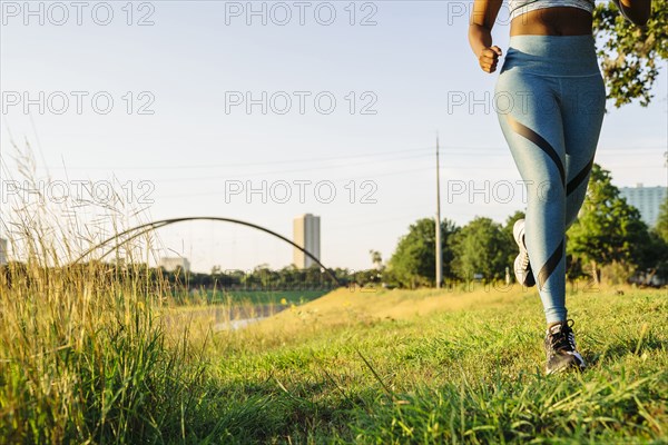 Legs of mixed race woman running in grass near waterfront