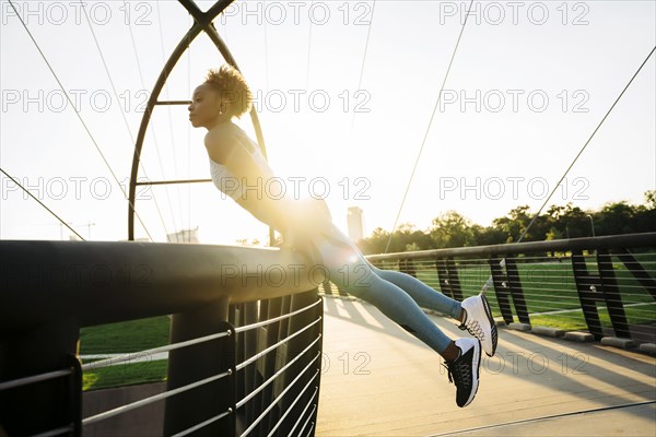 Curious mixed race woman leaning on bridge railing