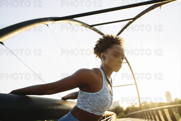 Portrait of mixed race woman stretching arms by pulling on railing