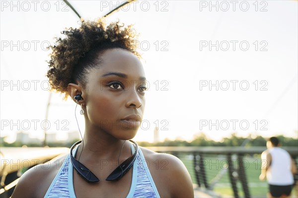 Mixed Race woman listening to earbuds on bridge