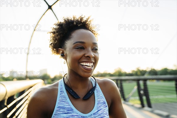 Mixed Race woman listening to earbuds on bridge and laughing