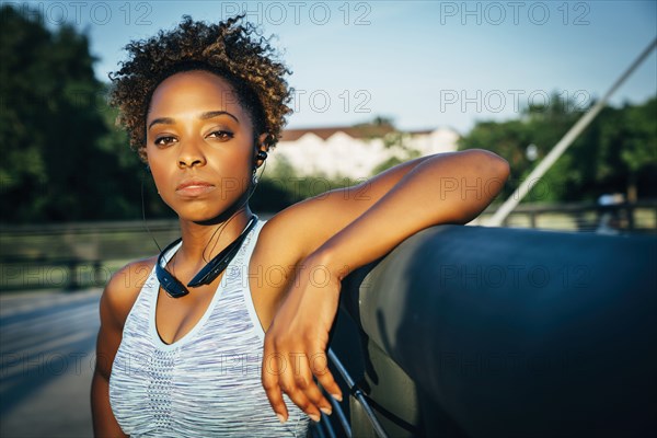 Serious mixed race woman listening to earbuds on bridge