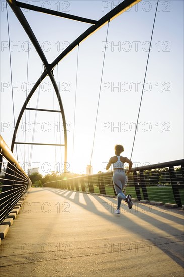 Distant mixed race woman running on bridge