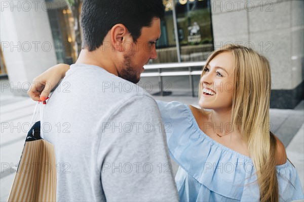 Caucasian couple hugging and carrying shopping bags