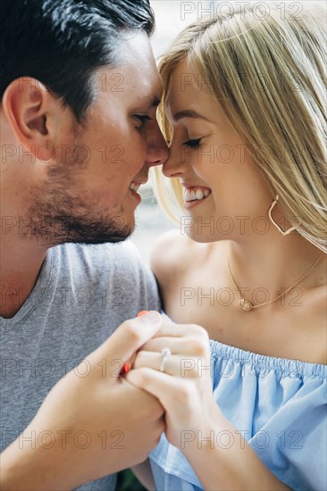 Smiling Caucasian couple holding hands and rubbing noses