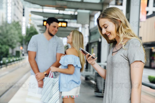 Caucasian woman at train station texting on cell phone