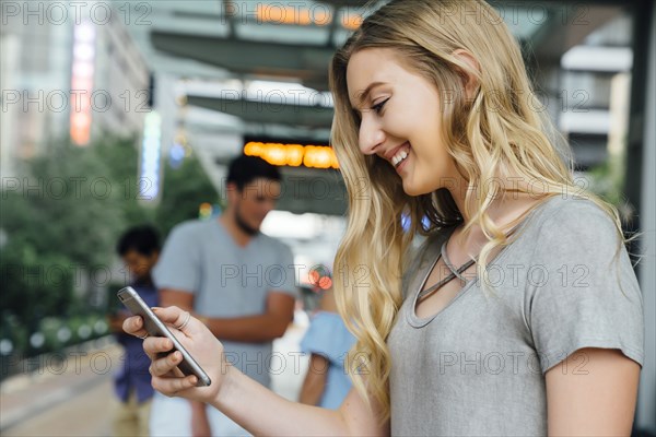 Caucasian woman at train station texting on cell phone