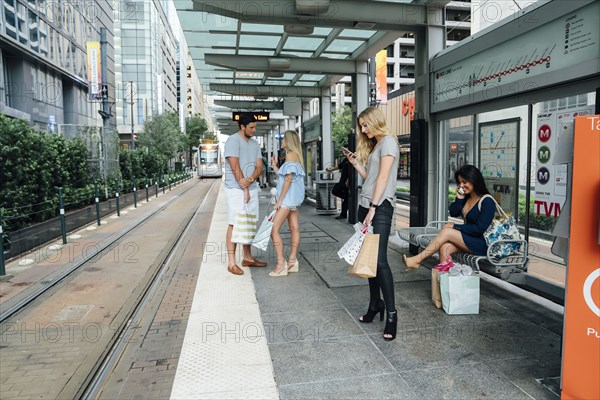 People at train station using cell phones