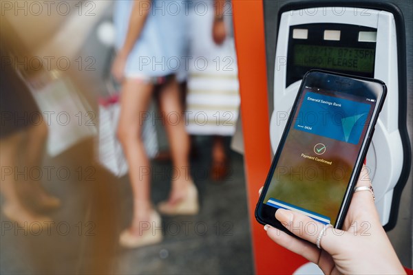 Hand of woman paying at kiosk using cell phone