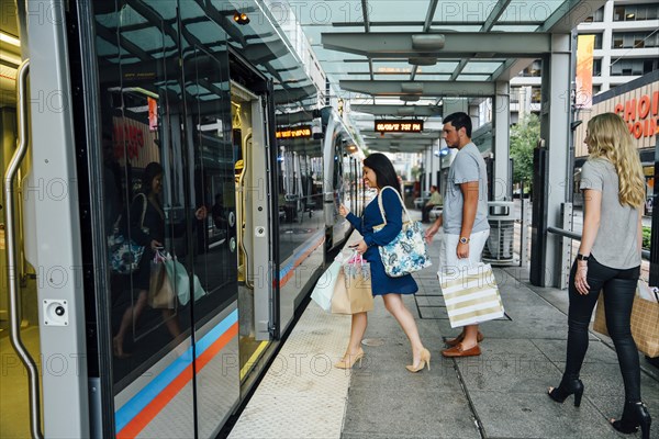 Friends boarding train carrying shopping bags