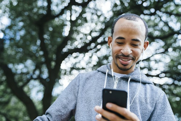 Black man listening to cell phone with earbuds