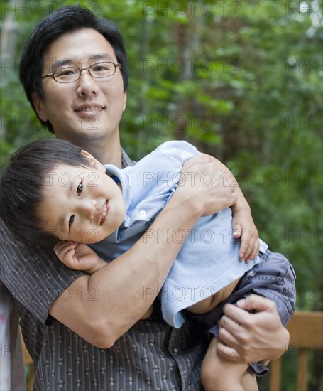 Asian father carrying son