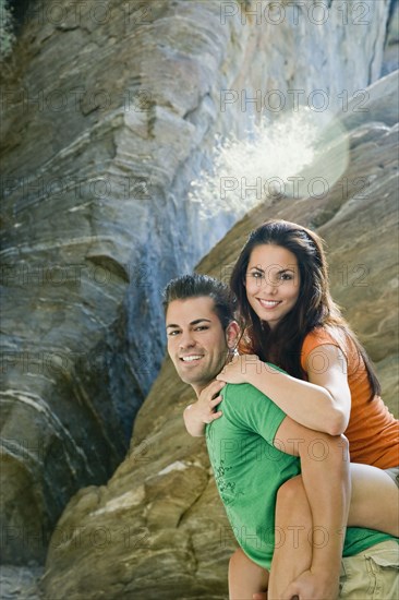 Hispanic man giving girlfriend piggyback ride