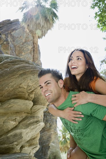 Hispanic man giving girlfriend piggyback ride