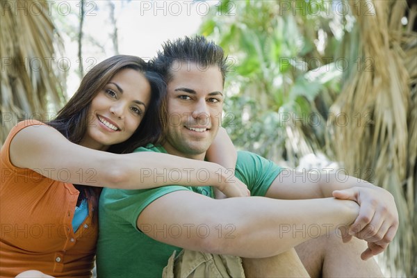 Hispanic couple hugging in tropical area