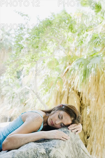 Hispanic woman sleeping on rock