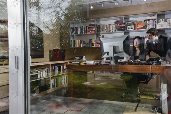 Mixed race businesswoman sitting at desk with co-worker