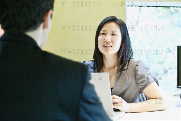 Asian businesswoman talking to co-worker