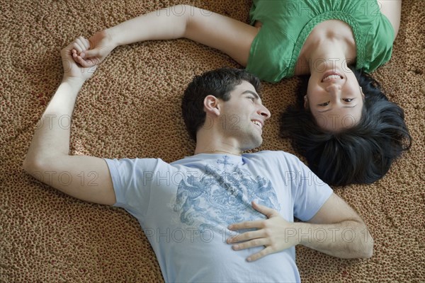 Couple laying on floor holding hands