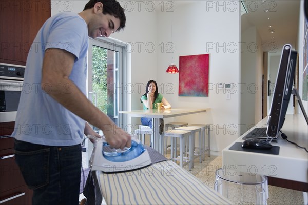 Husband ironing while wife watches