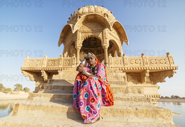 Indian woman in traditional clothes sitting near monument