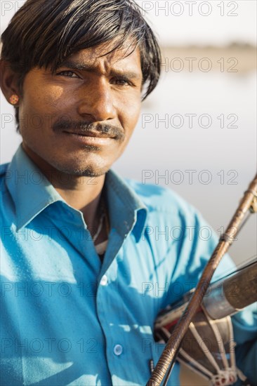 Close up of Indian man holding traditional instrument