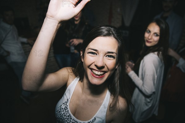 Smiling woman waving in nightclub