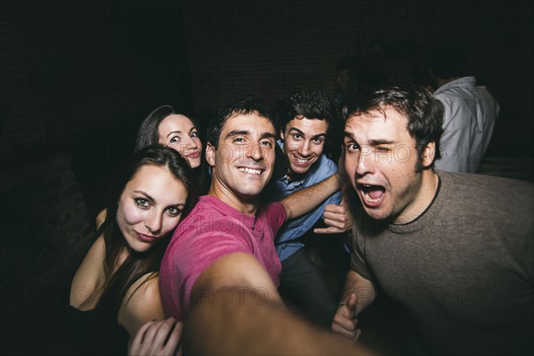 Smiling friends taking selfie in nightclub