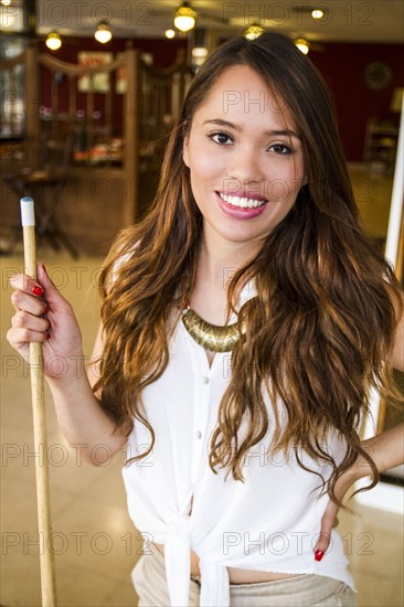 Hispanic woman holding pool cue