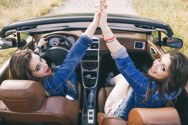 Women high-fiving in convertible