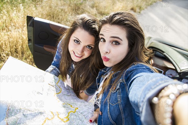 Women taking selfie with map on road trip