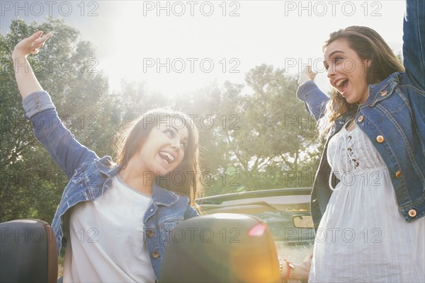 Women cheering in convertible