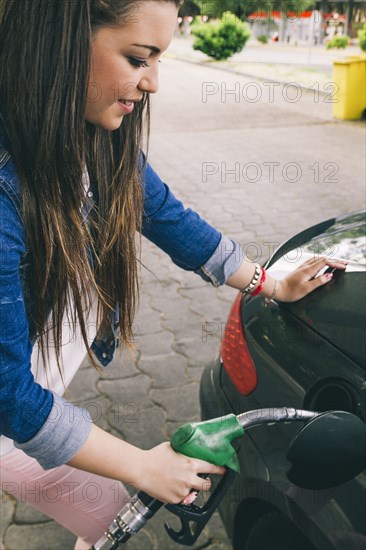 Hispanic woman fueling car in gas station