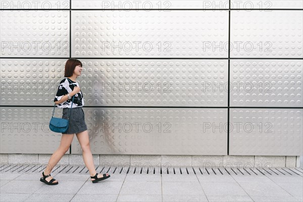 Chinese woman walking on sidewalk