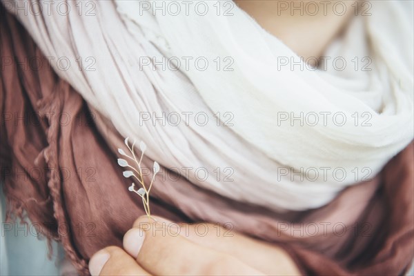 Caucasian woman holding delicate leaf near scarf