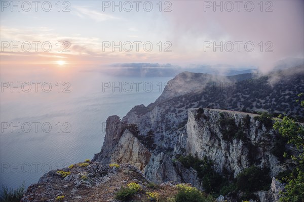 Sunrise from foggy ocean cliff