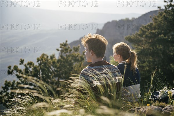 Caucasian couple sitting on hill admiring scenic view