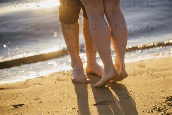 Legs of couple hugging at beach