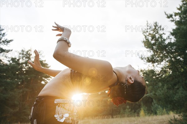 Caucasian belly dancer in field leaning backward