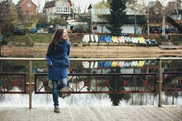 Smiling Caucasian woman leaning on bridge railing near river