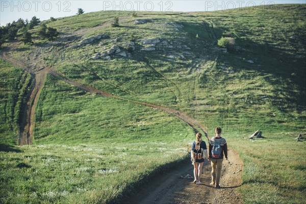 Caucasian couple walking on path toward hill