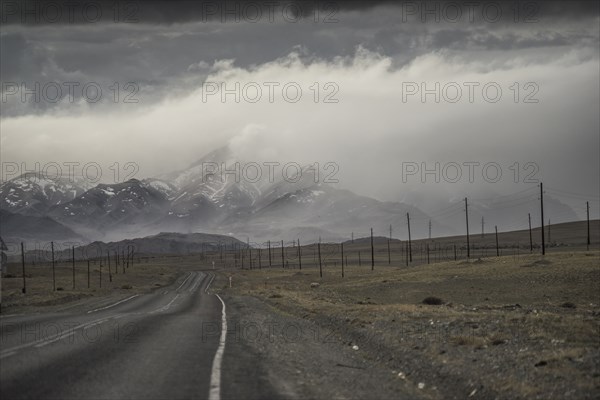 Clouds over road to mountain landscape