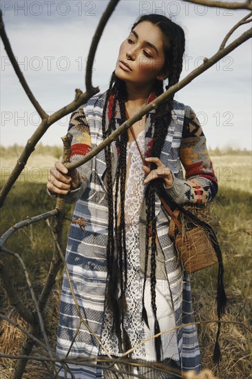 Caucasian woman wearing traditional clothing holding branch