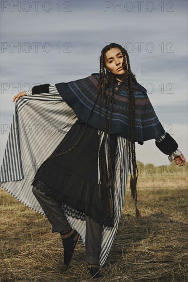 Caucasian woman wearing traditional clothing dancing in field