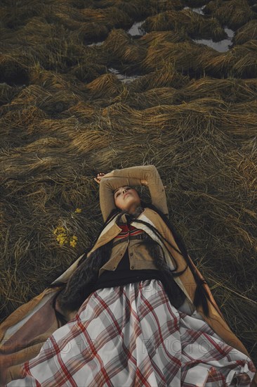 Caucasian woman wearing traditional clothing laying in grass