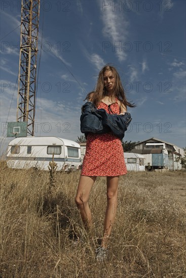 Serious Caucasian woman standing in field near trailers