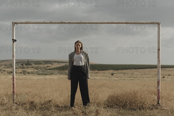 Serious location woman standing in worn soccer goal