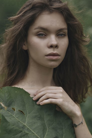 Caucasian woman covering chest with leaf